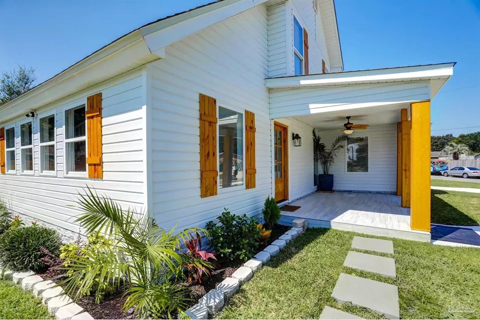 White cottage-style home with wood shutters and a palm-lined front garden