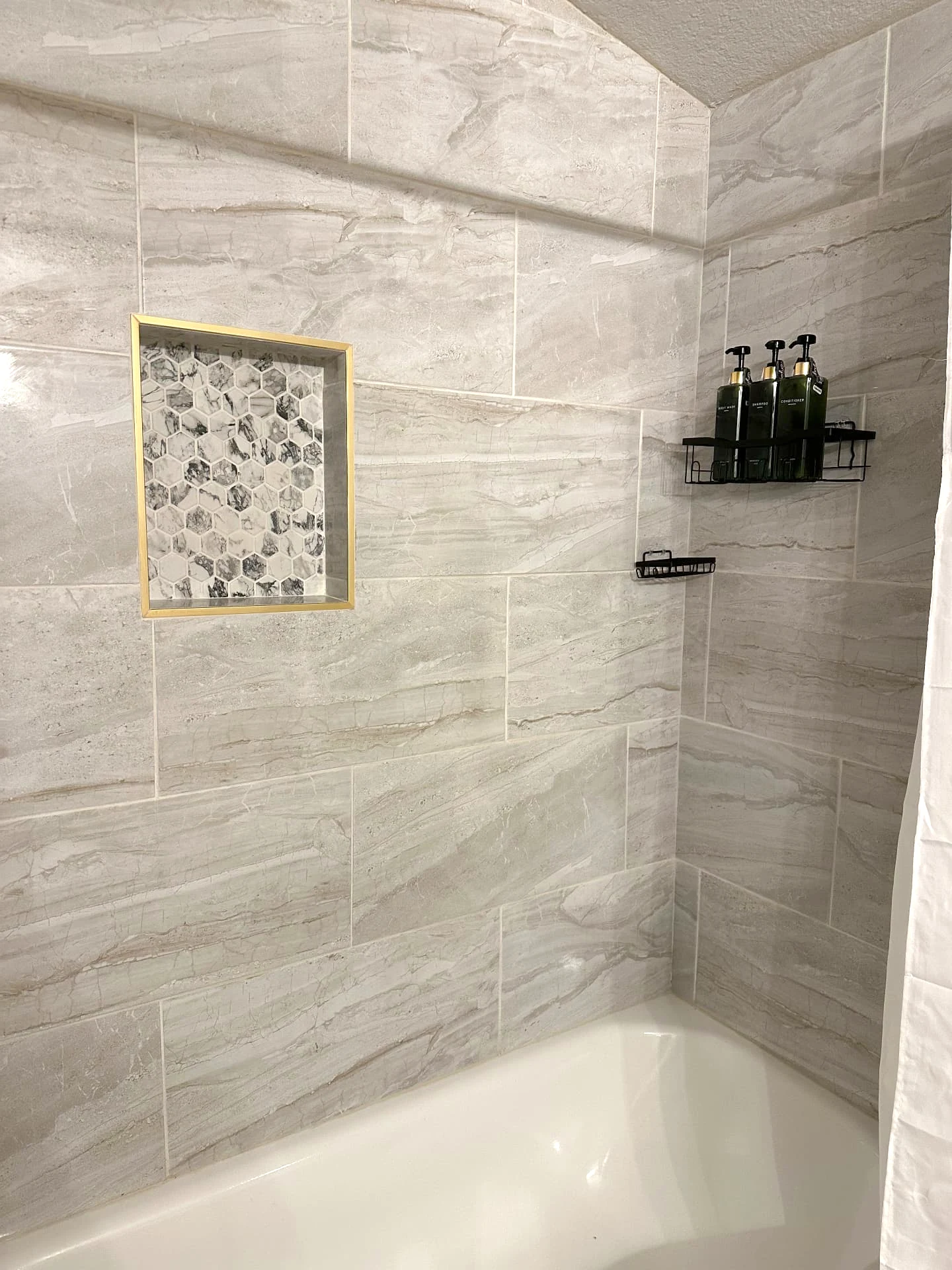 Bathtub and shower combo in the Cunningham Cottage primary en suite, with body wash, shampoo and conditioner in the wall caddy