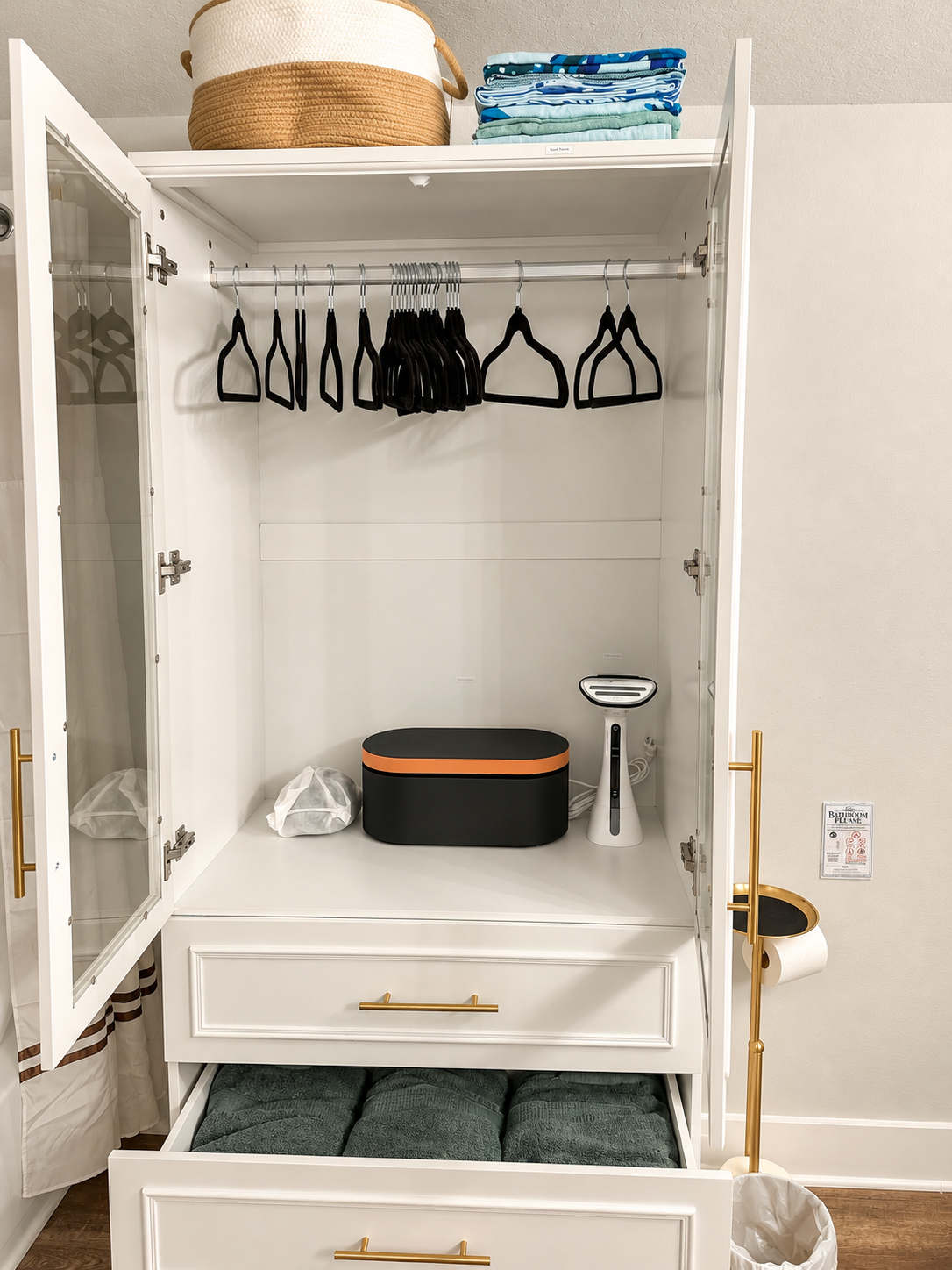 Open guest armoire with hangers, towels and garment steamer
