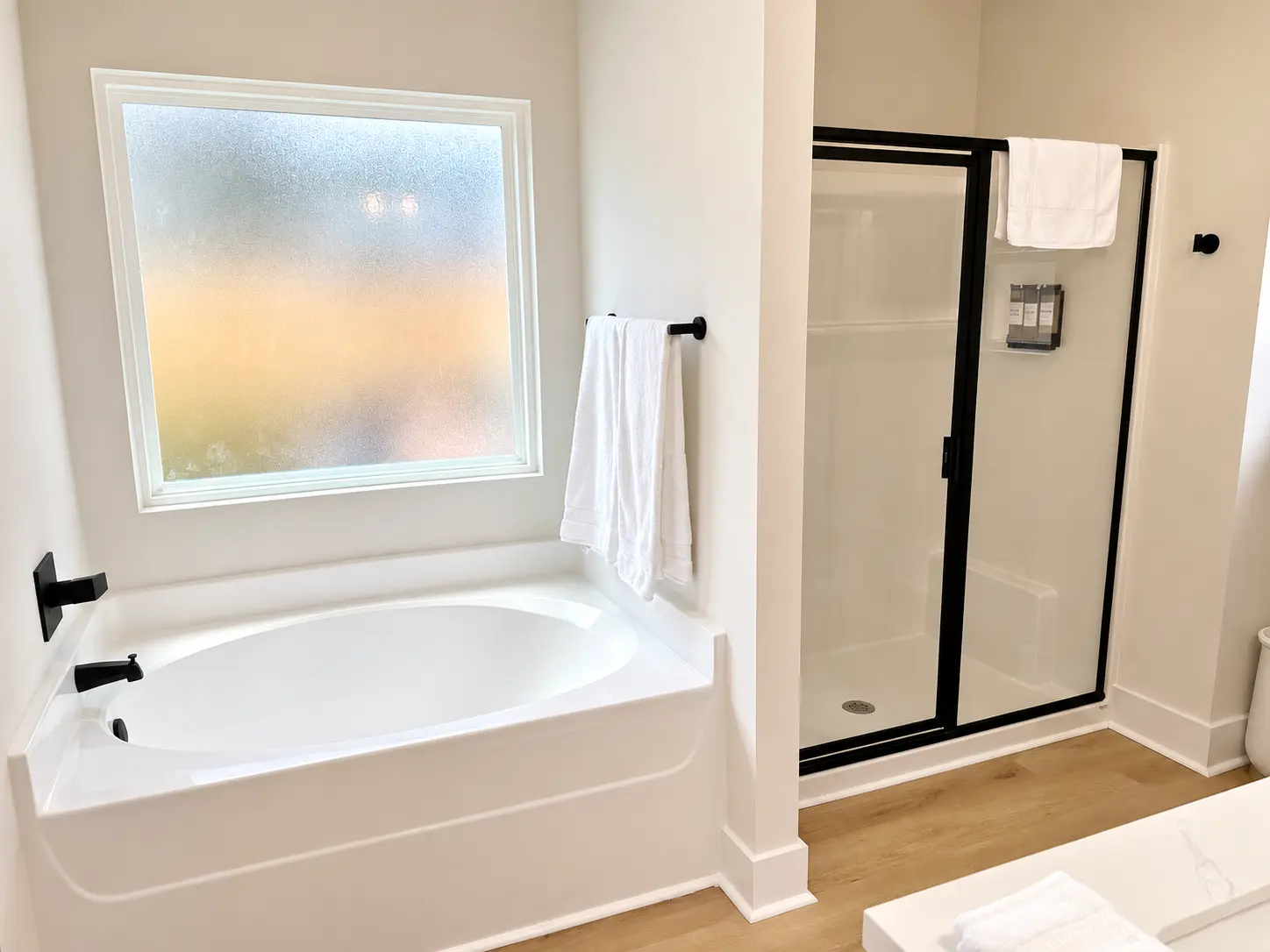Primary bath soaking tub beside a glass walk-in shower with plush towels