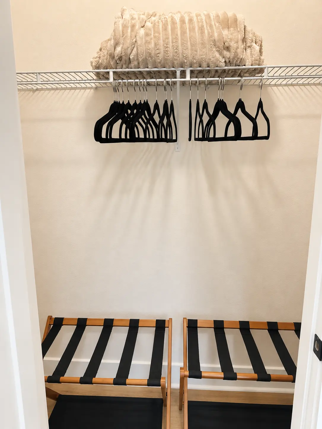 Bedroom closet with velvet hangers, extra blanket and two luggage racks