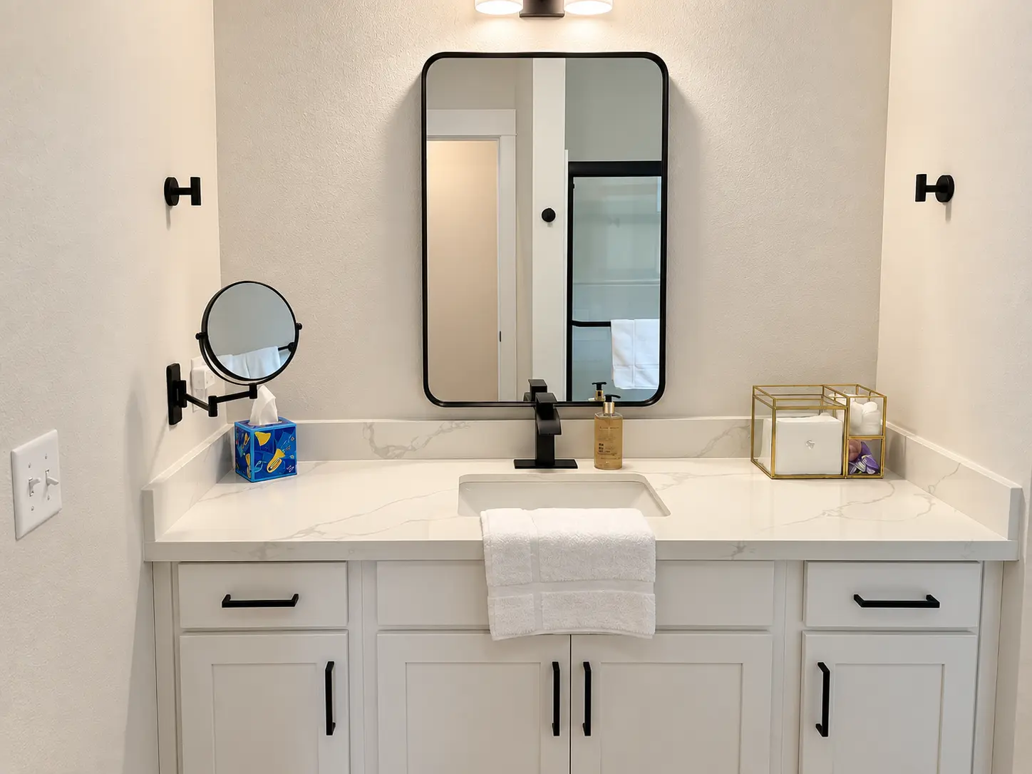 Second bathroom vanity with quartz counter, framed mirror and folded towels