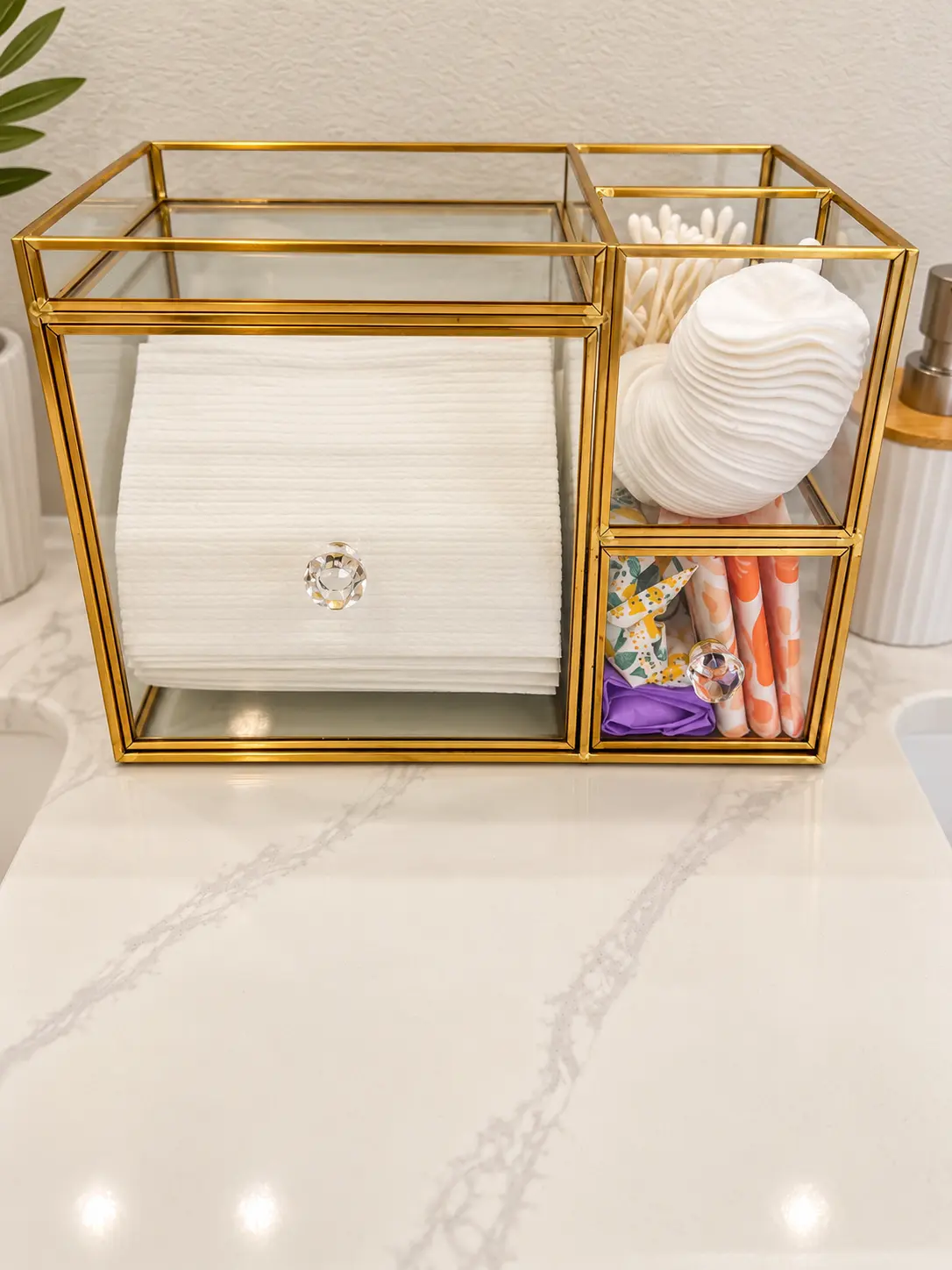 Brass and glass caddy stocked with cotton pads, swabs and guest essentials